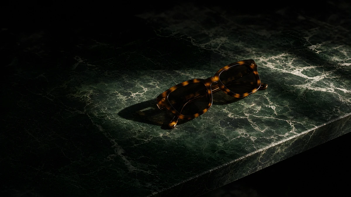 Tortoiseshell sunglasses casting a shadow on dark green marble