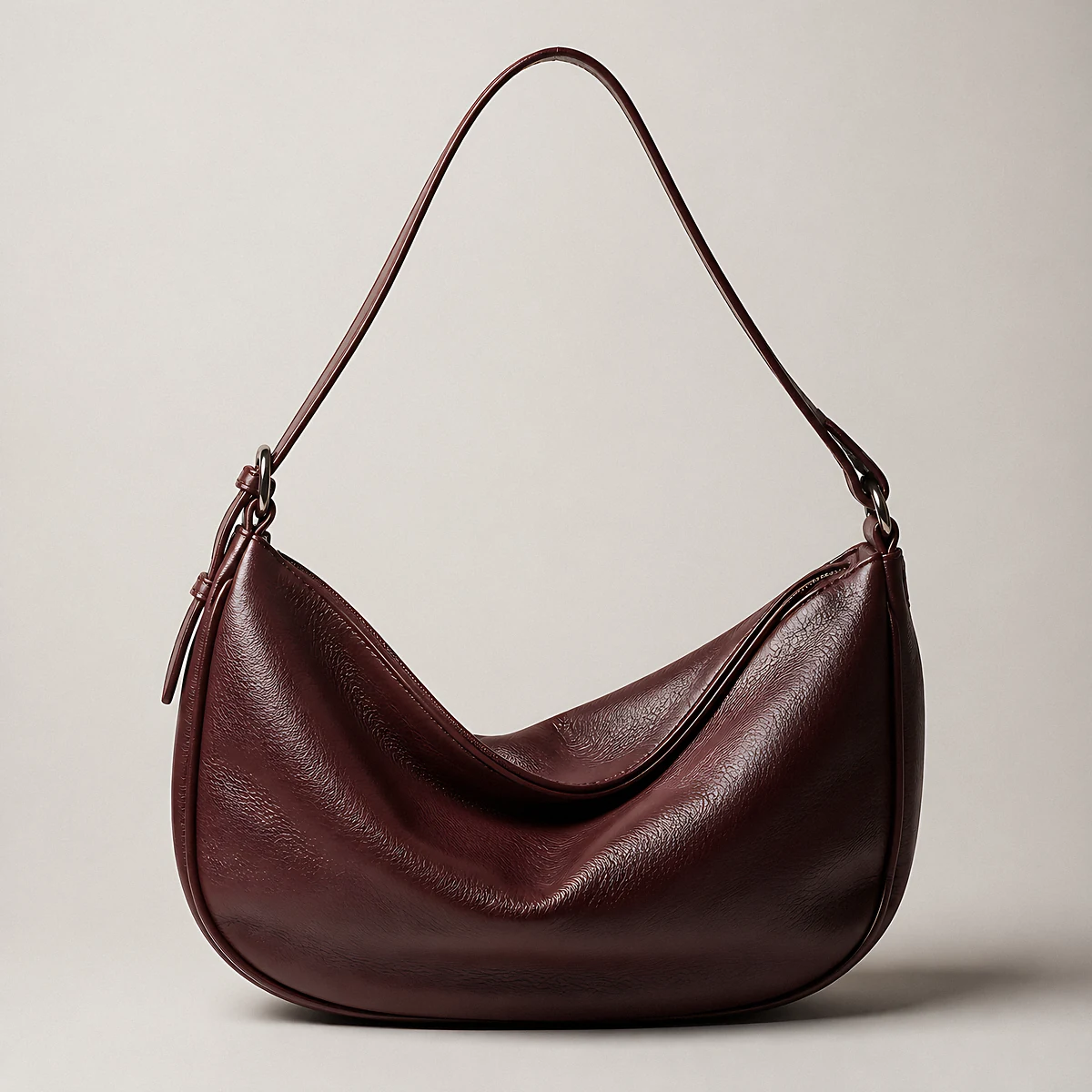 An oxblood leather half-moon shoulder bag photographed in the studio