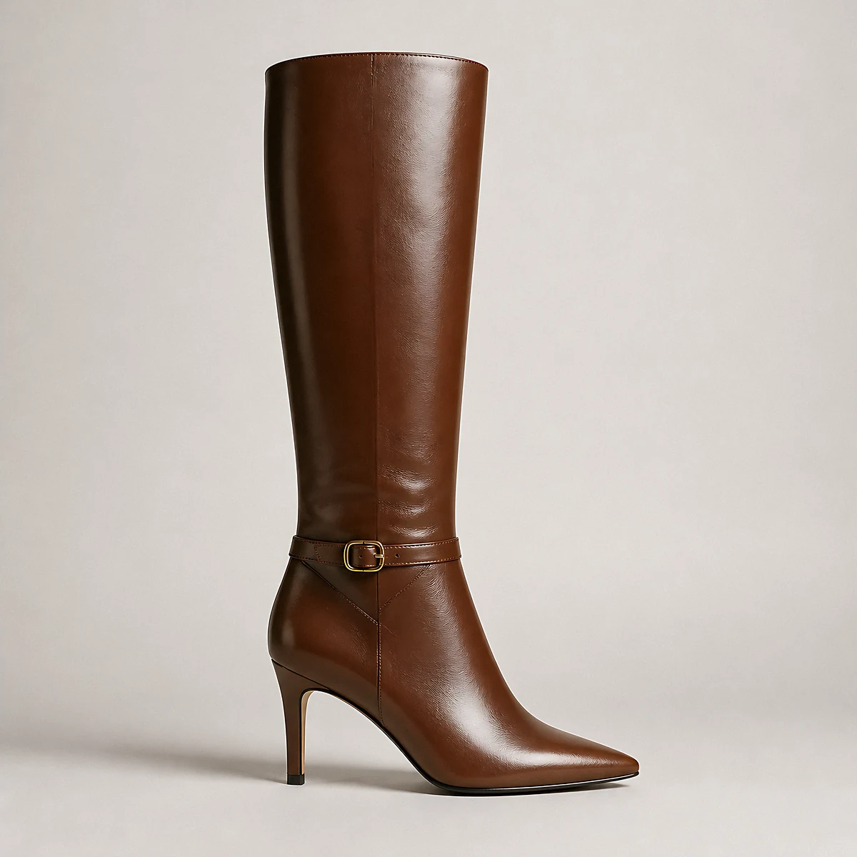 A single chestnut leather knee-high boot with a buckled ankle strap photographed in the studio