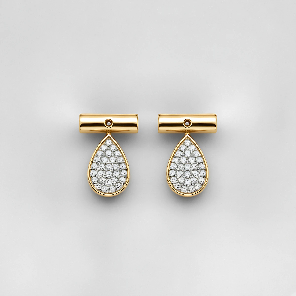 A pair of gold bar earrings with pavé diamond pear drops on a pale grey background
