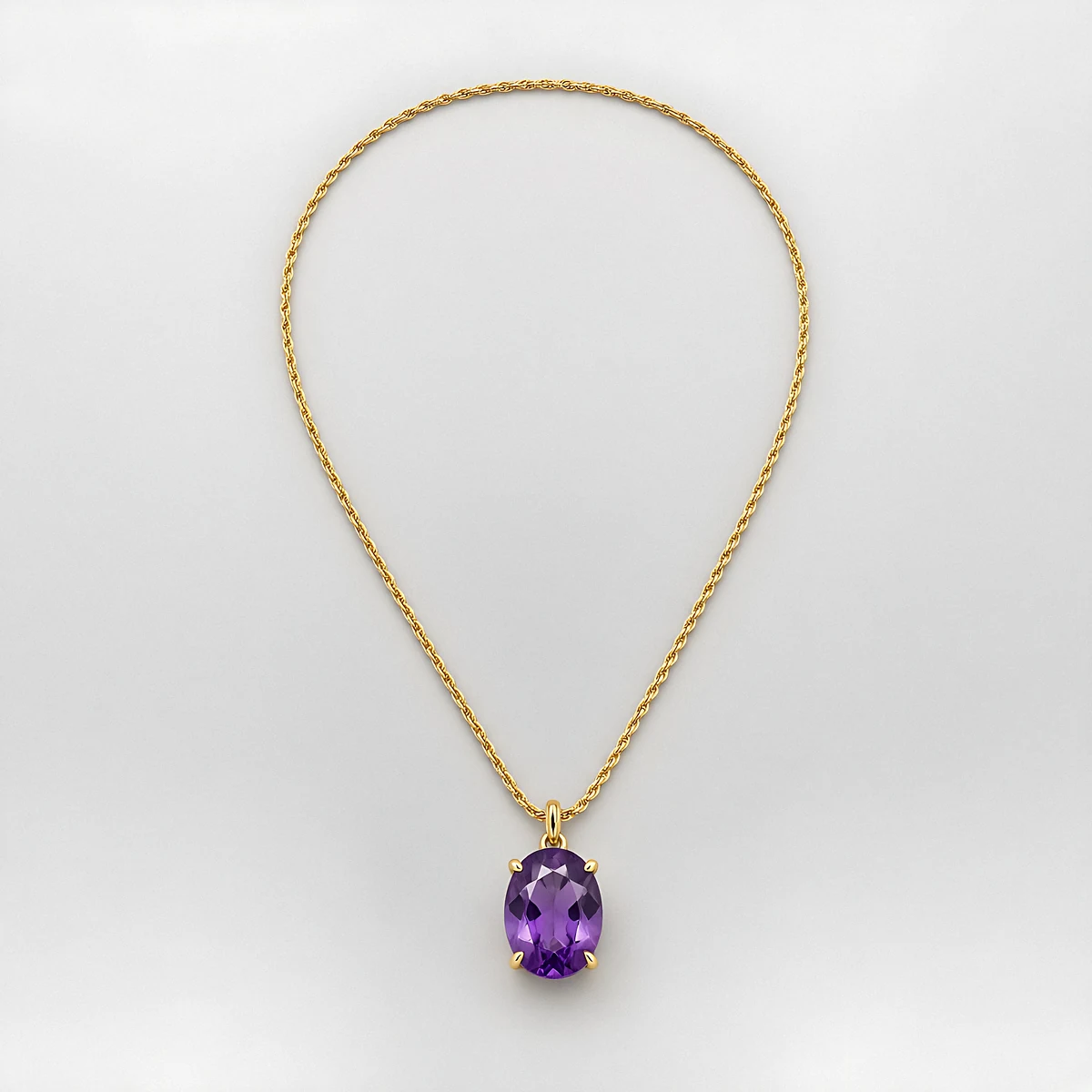 A long gold rope-chain sautoir with an oval amethyst pendant on a pale grey background