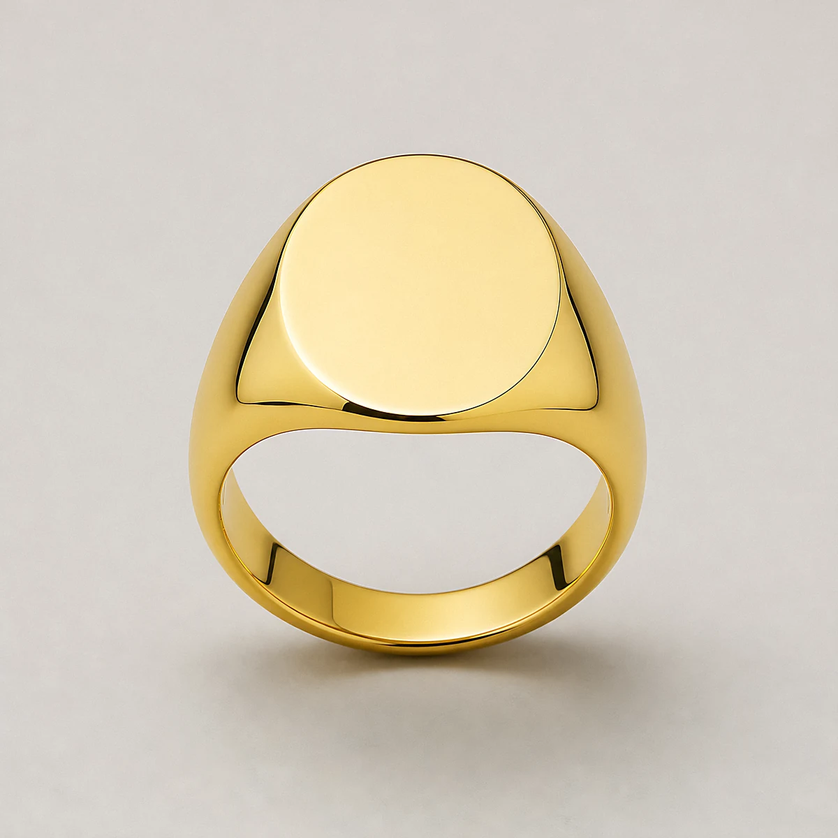 A polished yellow-gold oval signet ring, photographed in the studio