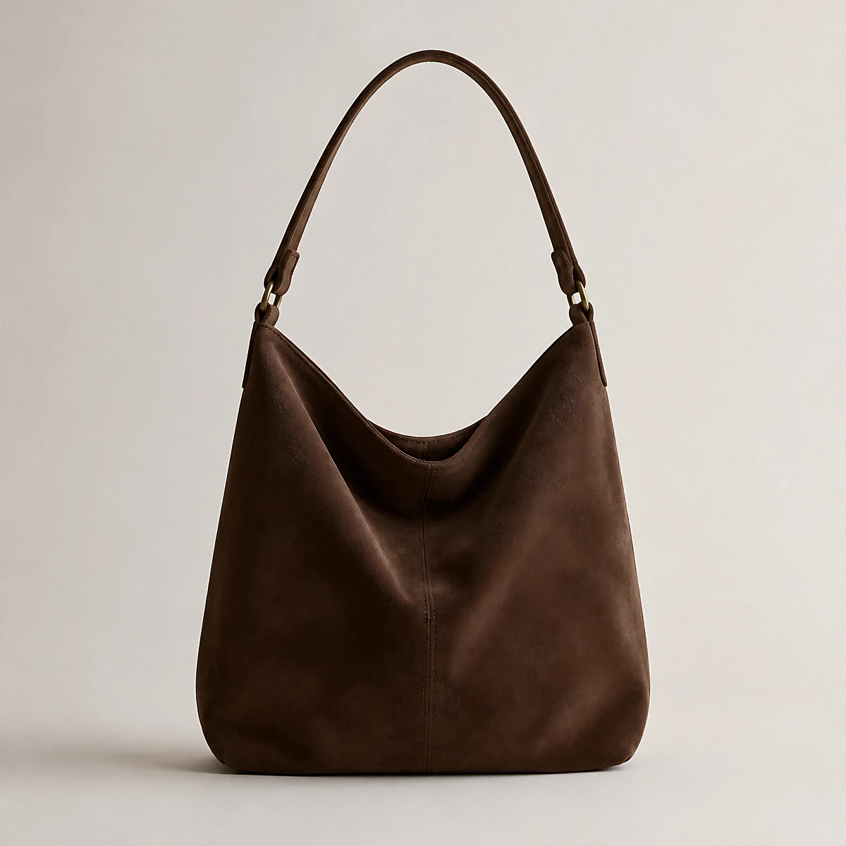 A slouchy chocolate-brown suede shoulder bag, photographed in the studio