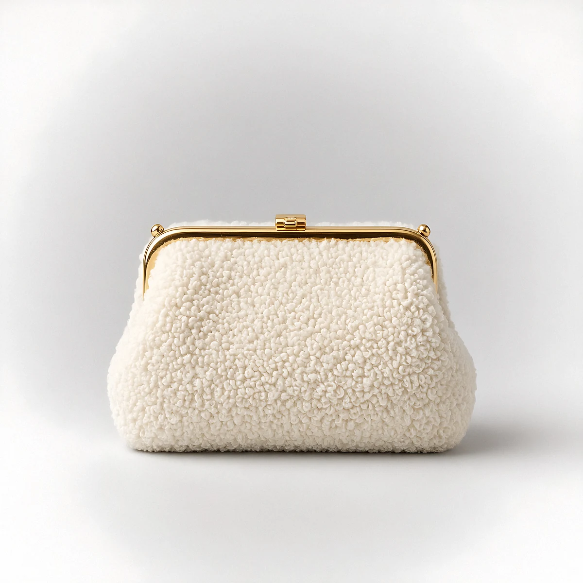 A cream shearling frame clutch with a gold clasp on a pale grey background