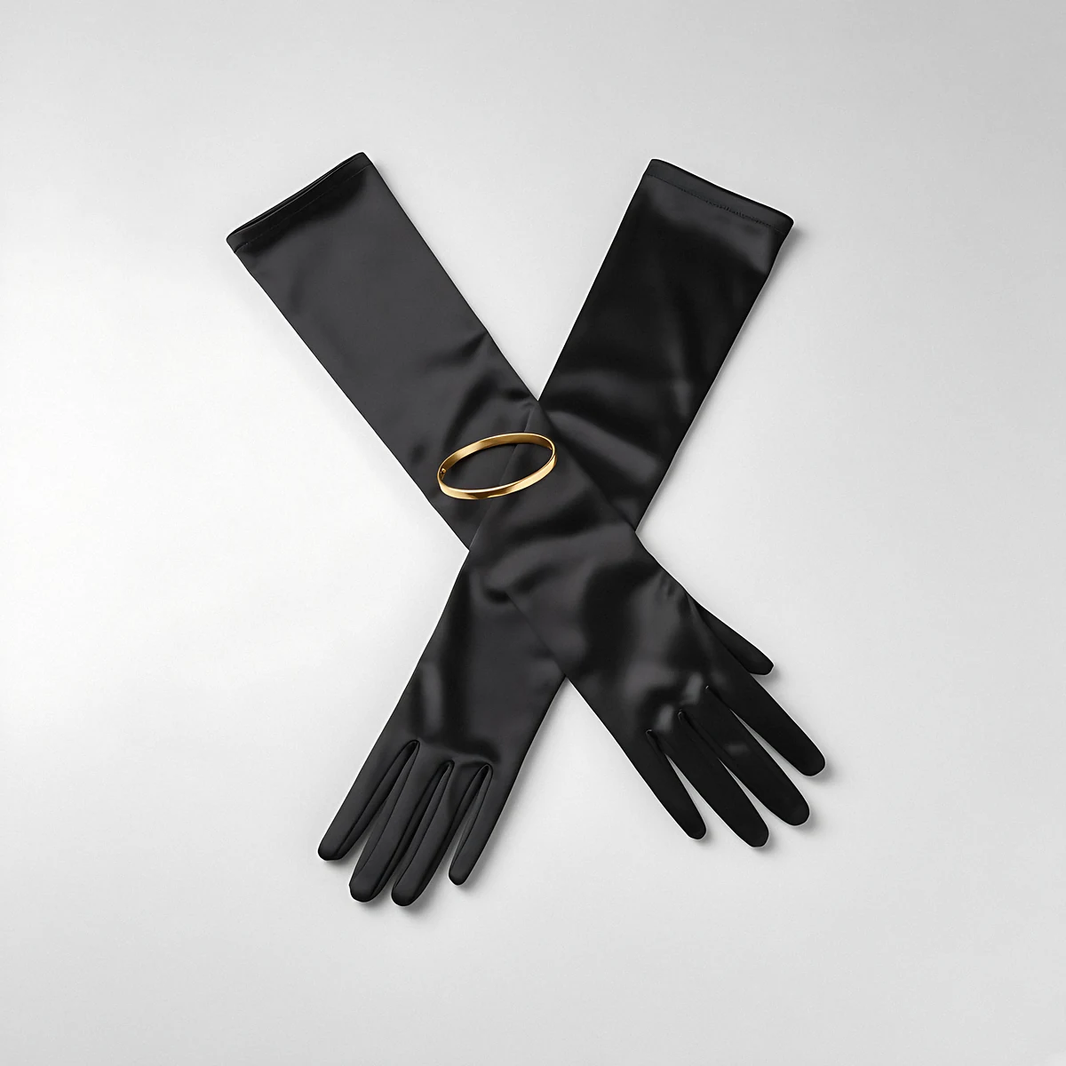 Long black satin opera gloves crossed, with a slim gold bangle, on a pale grey background