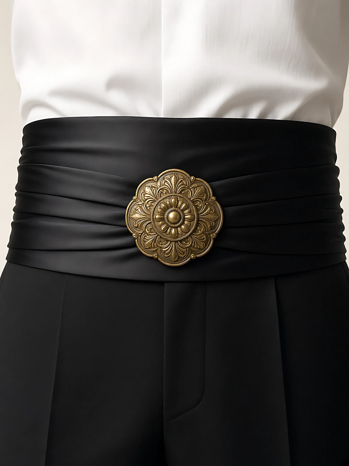 A black satin cummerbund with an antique gold medallion buckle over a white shirt